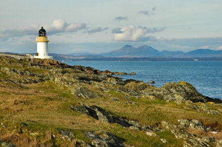 Picture of a lighthouse on a sea loch, mountains in the distance