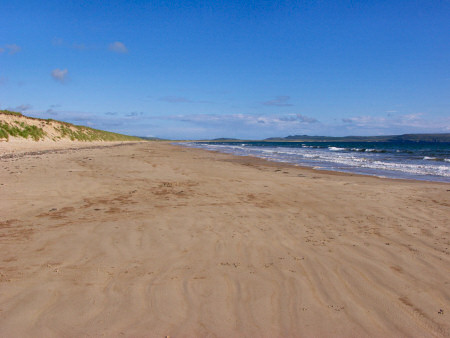 Picture of a beach with dunes behind it stretching into the distance
