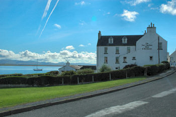 Picture of the Port Charlotte Hotel on Islay with the blue surface of Loch Indaal in the background