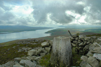 Picture of the summit of a hill (a marilyn) with a trig point and a view over a sound