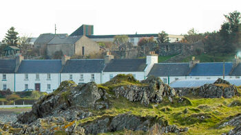 Picture of a modern school building just visible behind a row of older houses