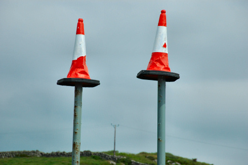 Picture of two traffic cones sitting on the top of two high poles