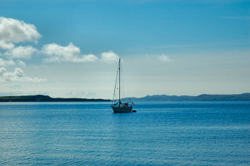 Picture of a sailing yacht anchored in a wide bay on a beautiful sunny day