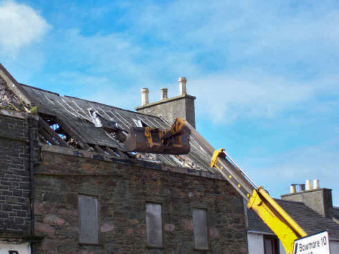 Starting to take down the roof Picture of a digger reaching up to a roof