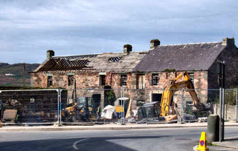 Picture of a hole in the ground with diggers and other machinery where a building used to stand