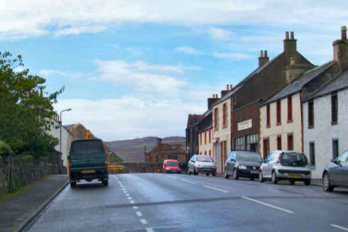 Picture of a view along a street with hills visible through a gap where a building used to be