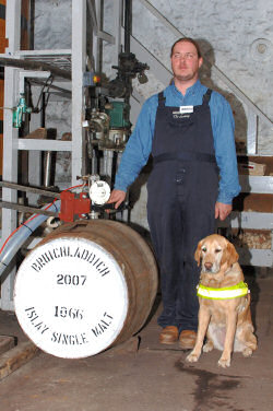 Picture of a man with his guide dog next to a whisky cask