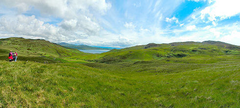 Picture of a panoramic view over a wide glen with a sound between two island at the end
