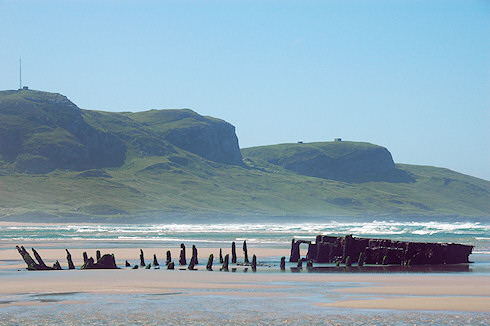Picture of a wreck on a beach on the Isle of Islay with the Kilchoman Crags in the background