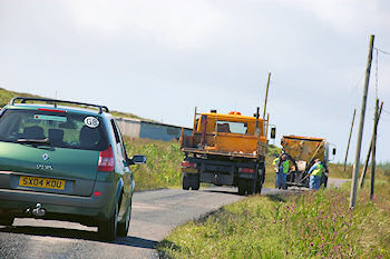 Picture of a car behind two council road repair lorries