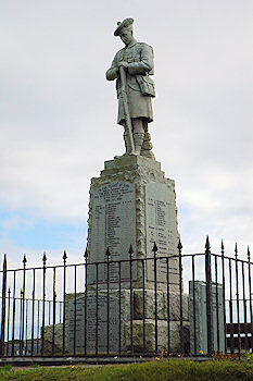 Picture of the war memorial in Port Ellen, Islay. Statue of a soldier on top of a plinth with the names of the fallen