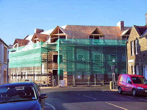 Picture of the front of an under construction hotel with the roof nearing completion