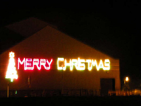 Picture of the words 'Merry Christmas' in neon lighting on the side of a warehouse