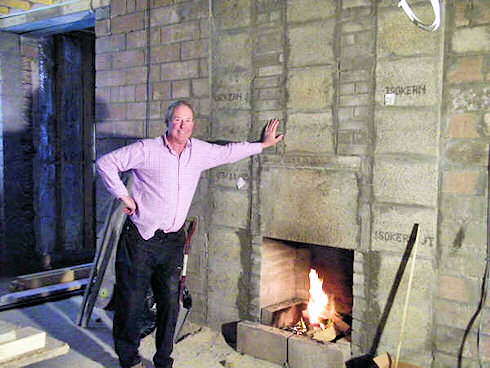 Picture of a man standing in front of a future fireplace in an under construction hotel