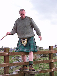 Picture of a walker in kilt climbing over a stile