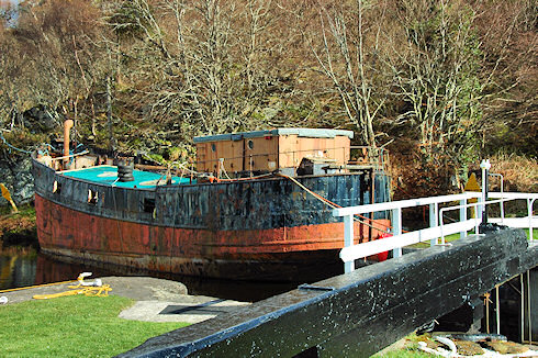Picture of an old puffer moored next to a lock