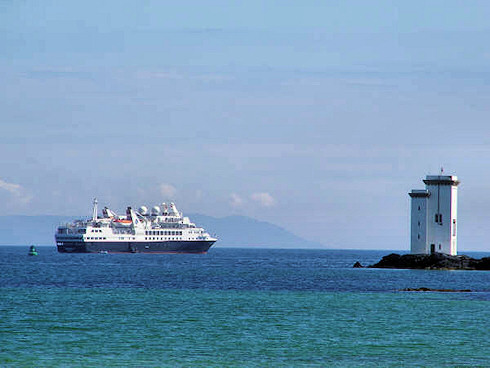 Picture of a black cruise liner anchored near a lighthouse
