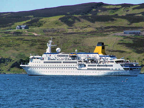 Picture of a large white cruiseliner off a steep shore