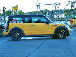 Picture of a yellow Mini Clubman with the lettering hansemalt.de on the side parked in a small harbour