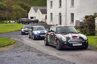 Picture of three Mini Cooper cars in a row in front of a house
