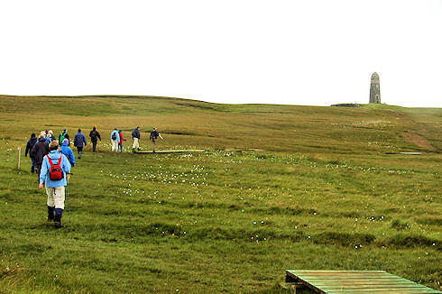 Picture of a group of walkers on slightly hilly ground, a monument in the distance