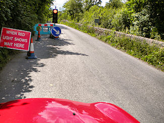 Picture of a temporary traffic light with the sign 'When Red Light Shows Wait Here'