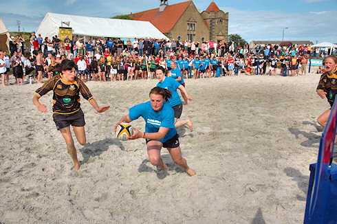 Picture of a player about to score a try in a beach rugby game