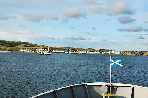 Picture of the view from a ferry arriving in a small island port, the Scottish Flag (Saltire) flying on the bow