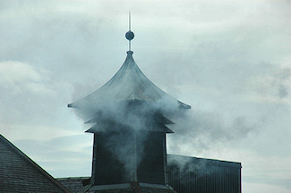 Picture of a pagoda at a whisky distillery with peat smoke billowing out