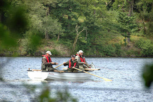 Picture of a boat with a rower and two men fly fishing