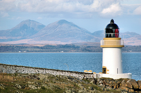 Picture of a small lighthouse with some distinctly shaped mountains in the background