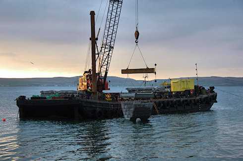 Picture of a barge crane lowering a 'special mattress' for a waterworks outlet into the water