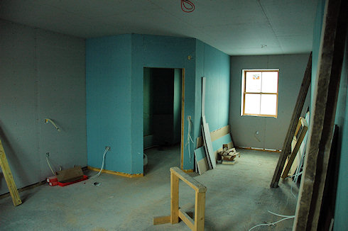 Picture of a guest room in an under construction hotel, the plasterboard has been put up and parts of the bathroom are ready