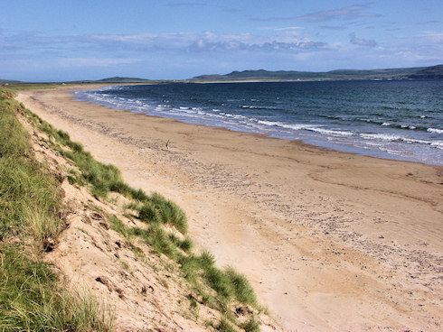 Picture of a long beach, bending in a slight curve around a wide bay