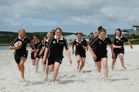 Picture of the Islay Womens Rugby Team running towards the camera on the beach in Port Ellen