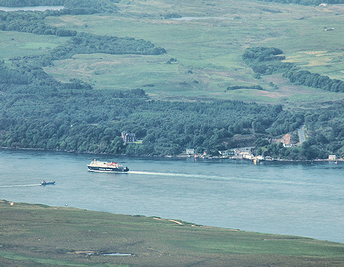 Picture of a Calmac ferry passing a small ferry port, seen from high above