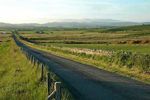 Picture of a single track road stretching in the distance on a sunny June evening