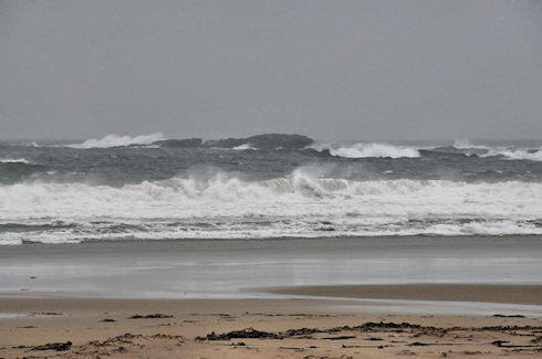 Picture of a beach and some rocks in the sea on a grey and rainy day