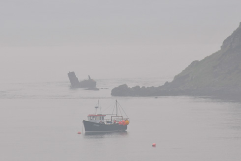 Picture of an anchored boat and a boat wreck on a very hazy day