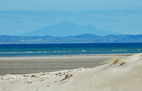 Picture of a view across a beach to another island with a third island in the background