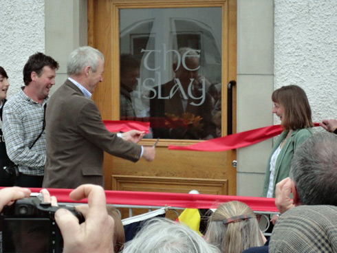 Picture of a man cutting the ribbon opening a hotel called the islay