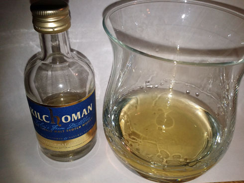 Picture of a miniature bottle of Kilchoman Inaugural Release Islay single malt whisky next to a whisky glass