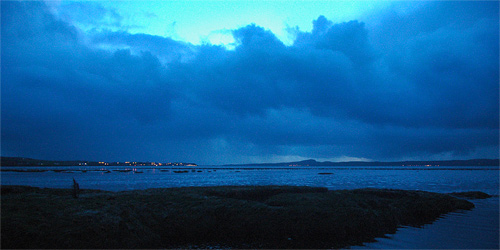 Picture showing a sea loch at last light, only some fading light visible behind some clouds