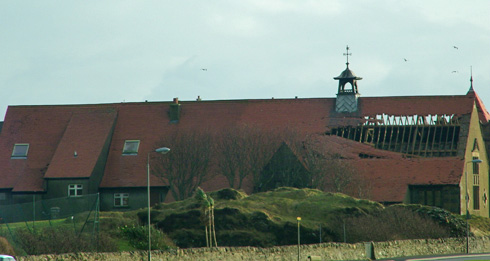 Picture of a storm damaged community hall with about a quarter of the roof missing