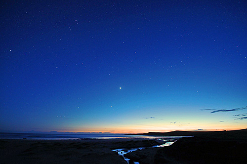 Picture of a beach in the gloaming, stars starting to appear in the sky