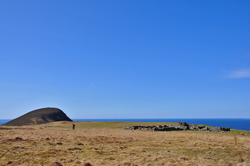 Picture of some ruins with a round shaped hill in the background