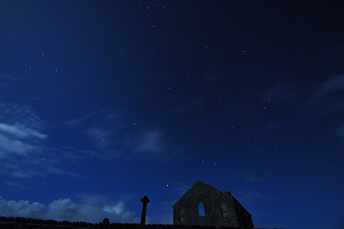 Picture of a church and a Celtic cross under a moonlit night sky