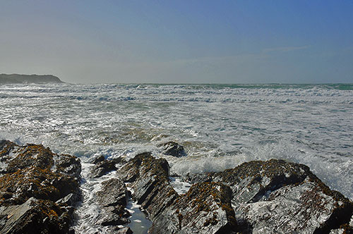 Picture of a bay with waves rolling in and on to a rocky shore