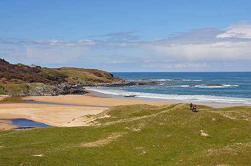 Picture of a bay with a golden sandy beach, seen from dunes behind