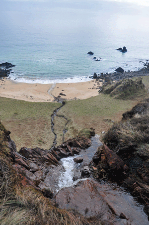 Animated gif of a waterfall running over a cliff towards a beach